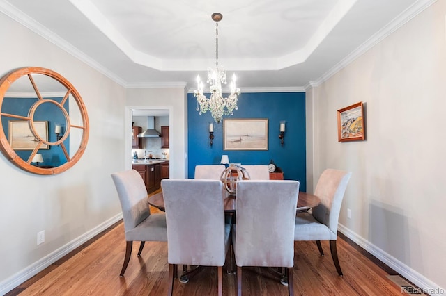 1519 Stonehill Ct, Castle Rock, CO 80104 - dining area featuring wood finished floors, a chandelier, a tray ceiling, baseboards, and crown molding