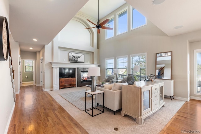 1519 Stonehill Ct, Castle Rock, CO 80104 - living area with light wood-style floors, ceiling fan, a glass covered fireplace, baseboards, and a high ceiling