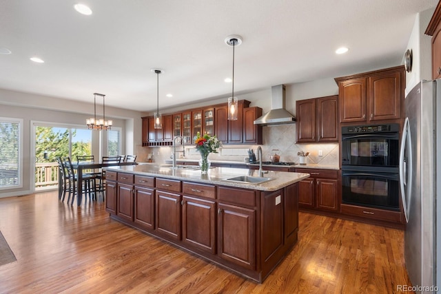 1519 Stonehill Ct, Castle Rock, CO 80104 - kitchen with wall chimney range hood, appliances with stainless steel finishes, a sink, a kitchen island with sink, and recessed lighting