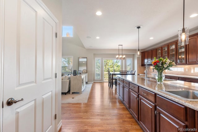 1519 Stonehill Ct, Castle Rock, CO 80104 - kitchen featuring light wood finished floors, recessed lighting, hanging light fixtures, glass insert cabinets, and a sink