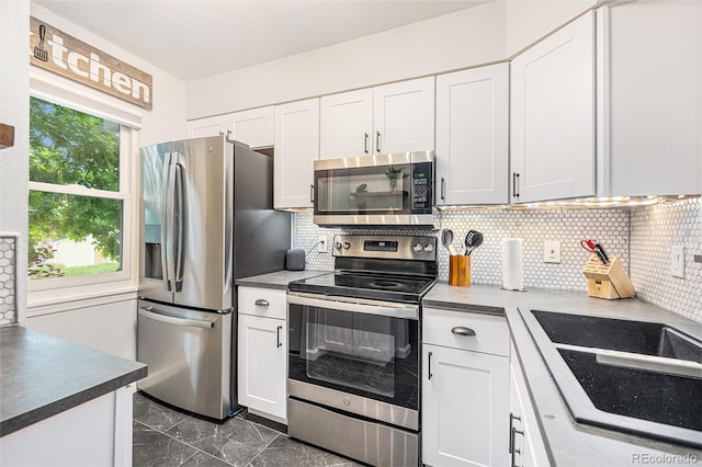 9519 W Coal Mine Ave Unit F, Littleton, CO 80123 - kitchen with appliances with stainless steel finishes, white cabinetry, backsplash, dark marble finish flooring, and dark countertops