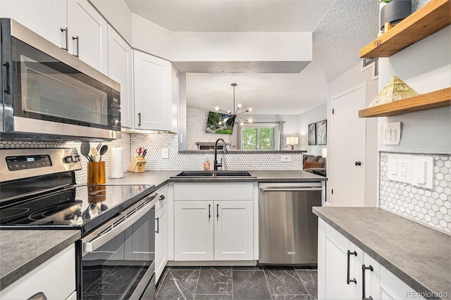 9519 W Coal Mine Ave Unit F, Littleton, CO 80123 - kitchen with appliances with stainless steel finishes, open shelves, dark marble finish floors, a chandelier, and white cabinetry