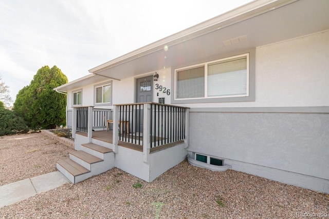 view of exterior entry with covered porch and stucco siding