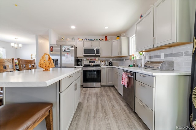 kitchen featuring backsplash, stainless steel appliances, light countertops, and a sink