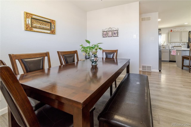 dining space with visible vents, baseboards, and light wood-style floors