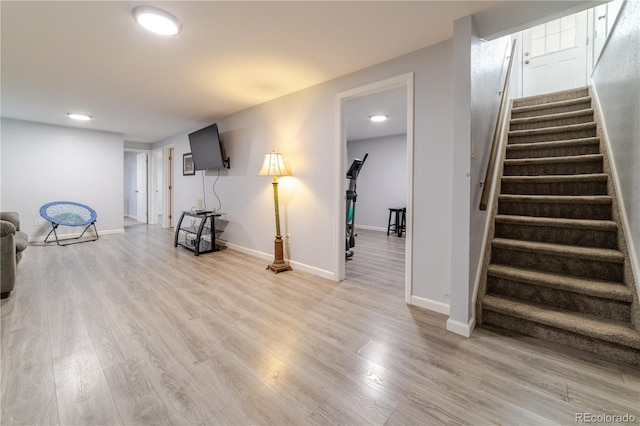 interior space with light wood-type flooring, baseboards, and stairs