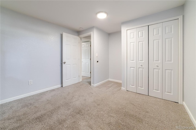 unfurnished bedroom featuring carpet flooring, baseboards, and a closet