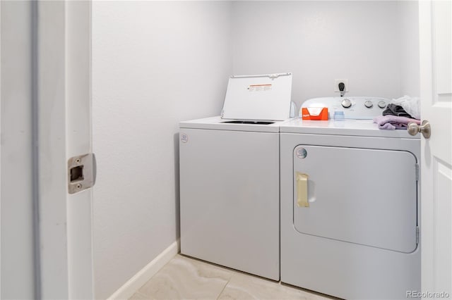 laundry room with light tile patterned floors, baseboards, separate washer and dryer, and laundry area