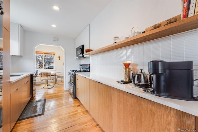 430 Osceola St, Denver, CO 80204 - kitchen with double oven range, open shelves, light countertops, tasteful backsplash, and arched walkways
