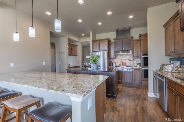 3012 Cathedral Park Vw, Colorado Springs, CO 80904 - kitchen with stainless steel appliances, a peninsula, under cabinet range hood, dark wood-style floors, and a kitchen bar