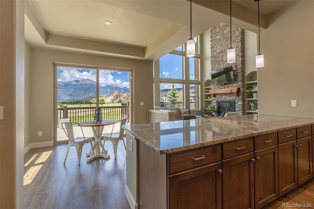 3012 Cathedral Park Vw, Colorado Springs, CO 80904 - kitchen with dark wood-style flooring, a fireplace, light stone countertops, decorative light fixtures, and open floor plan