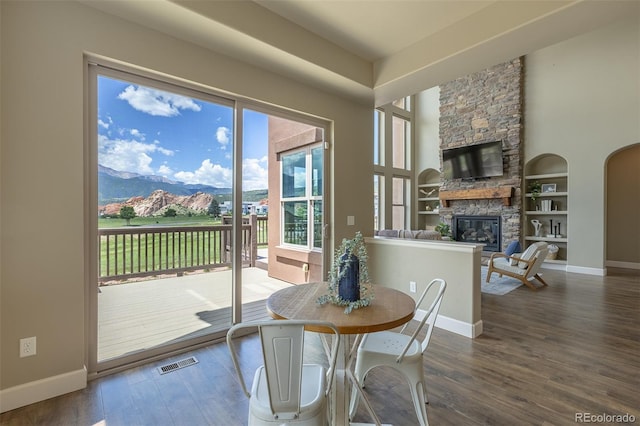 3012 Cathedral Park Vw, Colorado Springs, CO 80904 - dining area featuring wood finished floors, a stone fireplace, a mountain view, and arched walkways
