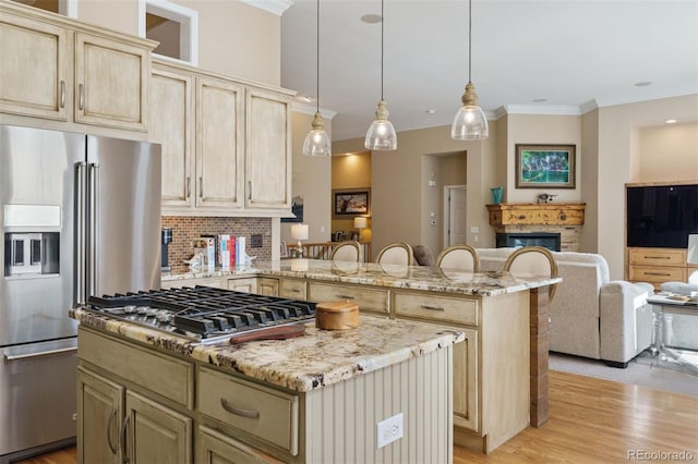 8528 Winter Berry Dr, Castle Pines, CO 80108 - kitchen featuring a glass covered fireplace, light wood finished floors, appliances with stainless steel finishes, light stone countertops, and a kitchen island