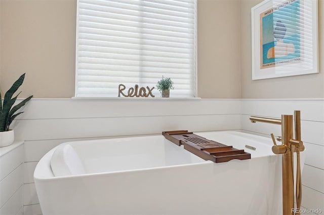 8528 Winter Berry Dr, Castle Pines, CO 80108 - bathroom featuring a washtub and a wainscoted wall