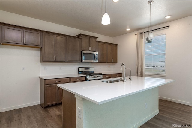 kitchen featuring appliances with stainless steel finishes, a center island with sink, decorative light fixtures, and sink