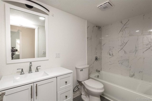 full bathroom with tiled shower / bath, vanity, a textured ceiling, and toilet