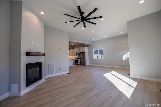 unfurnished living room with ceiling fan and light hardwood / wood-style flooring