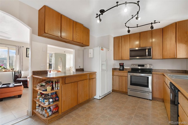 kitchen featuring open shelves, arched walkways, appliances with stainless steel finishes, and brown cabinetry