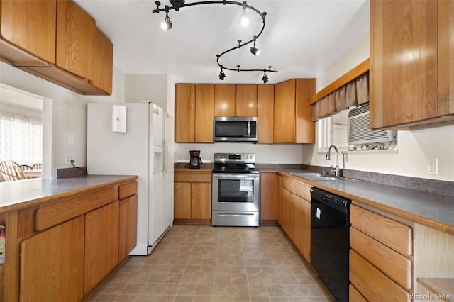 kitchen with dark countertops, brown cabinetry, appliances with stainless steel finishes, and a sink