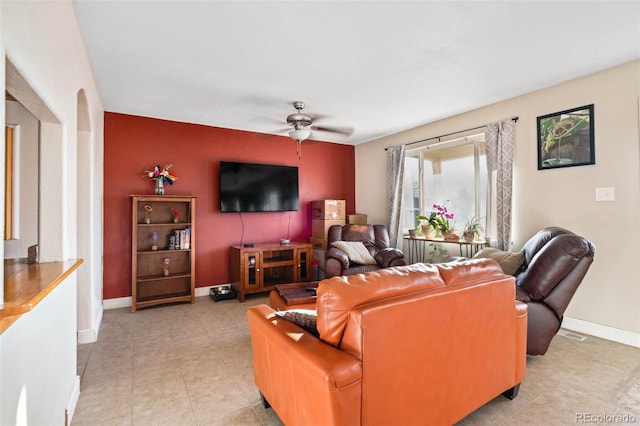 living room featuring a ceiling fan, baseboards, and arched walkways