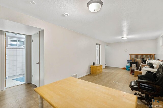 office featuring visible vents, light floors, a textured ceiling, and baseboards