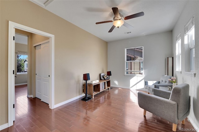 living area with wood-type flooring, ceiling fan, and a healthy amount of sunlight