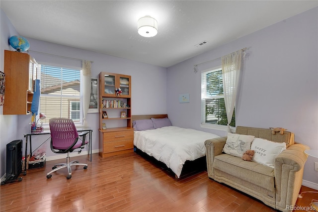 bedroom with hardwood / wood-style flooring and multiple windows