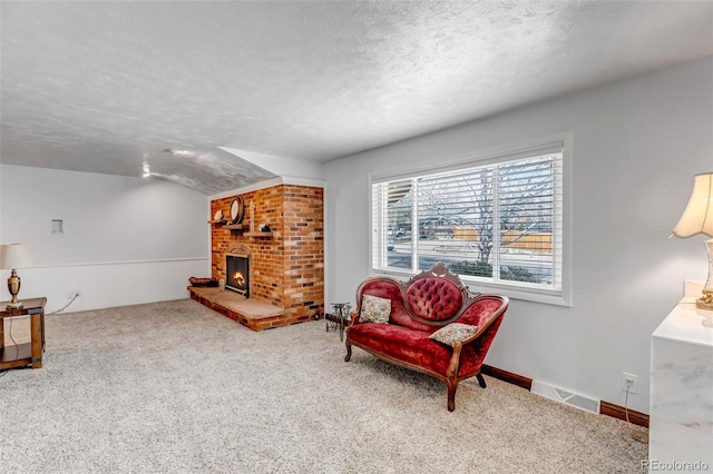 living area featuring a textured ceiling, carpet flooring, and a fireplace