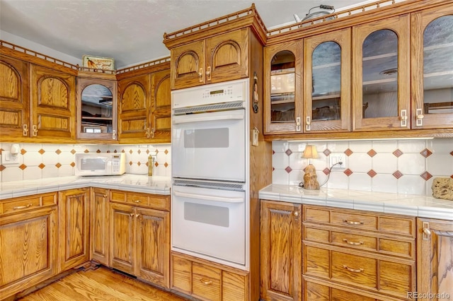 kitchen featuring white appliances, backsplash, and brown cabinets