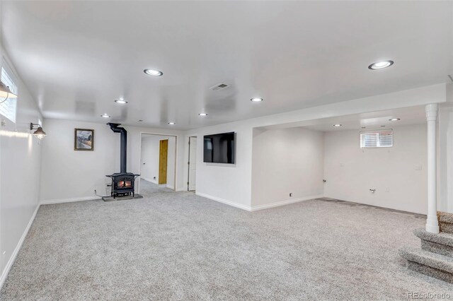 below grade area featuring a wood stove, carpet floors, recessed lighting, and baseboards