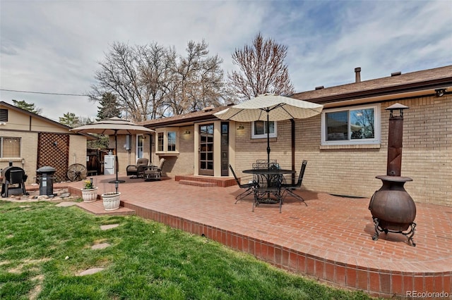 back of house featuring brick siding, a patio area, and a lawn