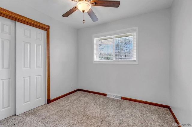 unfurnished bedroom featuring carpet, baseboards, ceiling fan, and a closet