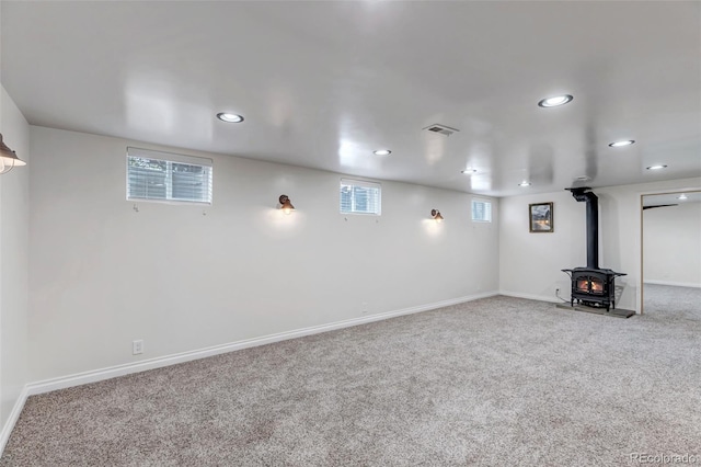 basement with a wood stove, carpet floors, recessed lighting, and baseboards
