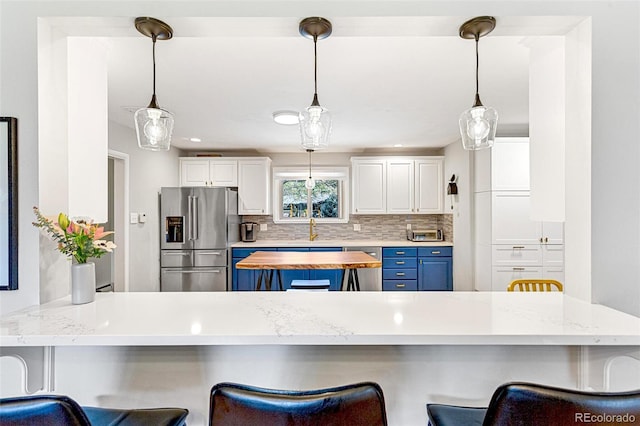 12256 W 34th Pl, Wheat Ridge, CO 80033 - kitchen featuring appliances with stainless steel finishes, blue cabinetry, decorative backsplash, a sink, and a kitchen bar