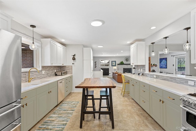 12256 W 34th Pl, Wheat Ridge, CO 80033 - kitchen featuring appliances with stainless steel finishes, tasteful backsplash, a stone fireplace, a sink, and hanging light fixtures