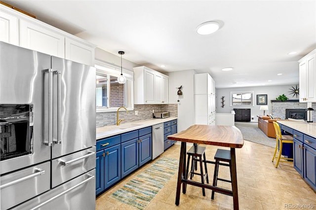 12256 W 34th Pl, Wheat Ridge, CO 80033 - kitchen featuring appliances with stainless steel finishes, blue cabinetry, a sink, decorative backsplash, and recessed lighting