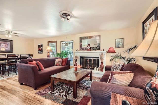 6940 W 63rd Ave, Arvada, CO 80003 - living room featuring light wood-style floors, a ceiling fan, and a glass covered fireplace