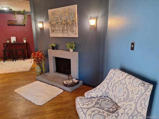 living area featuring hardwood / wood-style flooring and a brick fireplace