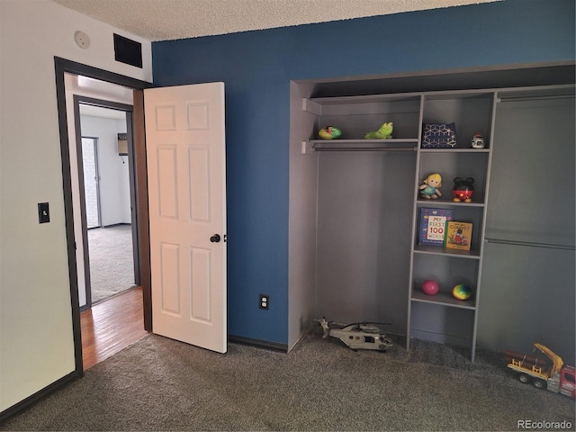 unfurnished bedroom with a closet, a textured ceiling, and dark hardwood / wood-style flooring