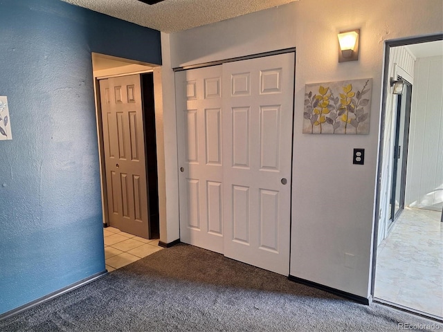 unfurnished bedroom with a textured ceiling, light tile patterned floors, a closet, light carpet, and a textured wall