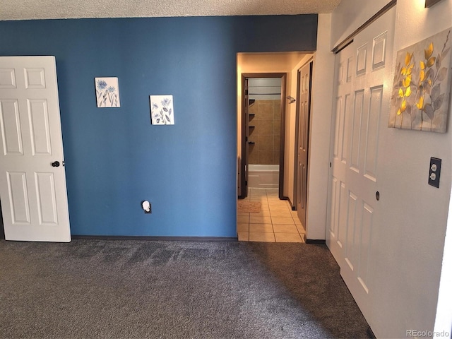 interior space featuring a textured ceiling, light tile patterned floors, a closet, and light carpet