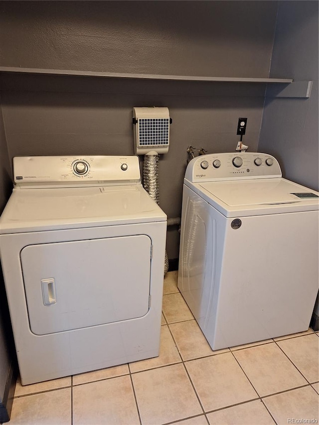 clothes washing area featuring laundry area, light tile patterned floors, and washing machine and dryer