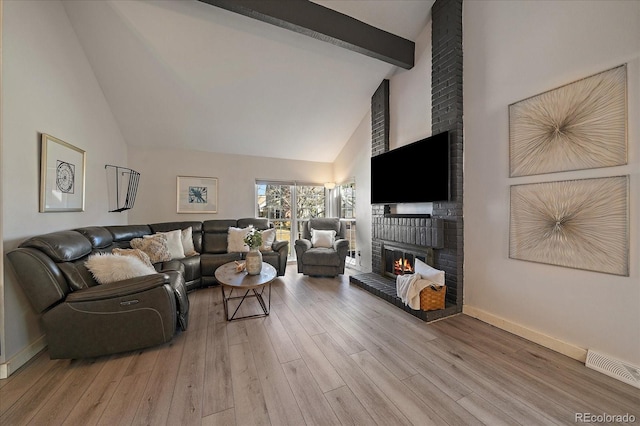 living room with a fireplace, visible vents, wood finished floors, high vaulted ceiling, and beamed ceiling