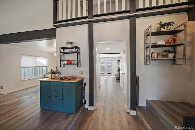 hallway with a high ceiling, wood finished floors, and baseboards