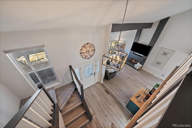 staircase featuring high vaulted ceiling, baseboards, and wood finished floors