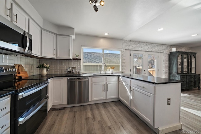 kitchen featuring dark countertops, light wood finished floors, stainless steel appliances, and a sink