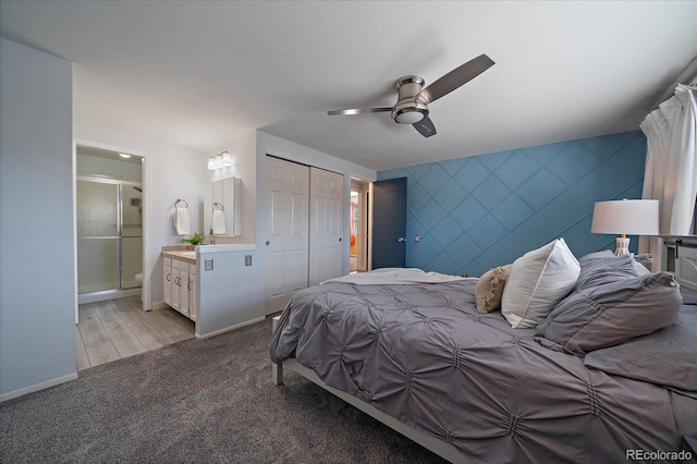 bedroom featuring an accent wall, baseboards, connected bathroom, and light colored carpet