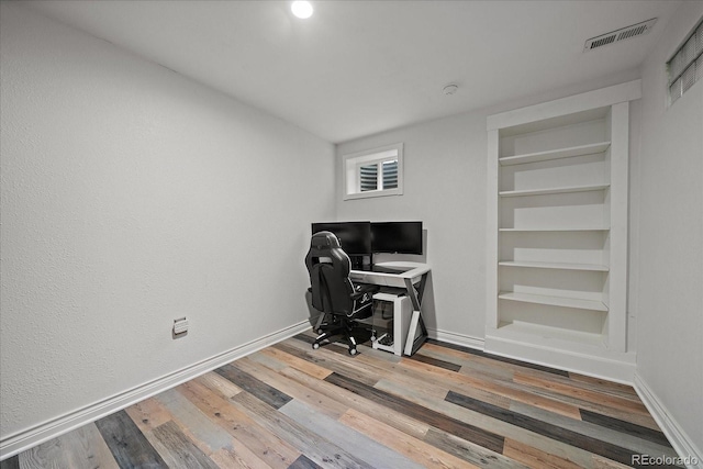 office featuring built in features, wood finished floors, visible vents, and baseboards