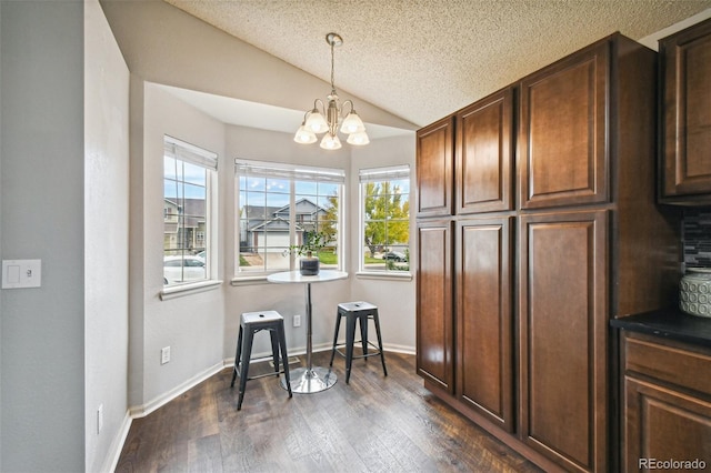 kitchen featuring vaulted ceiling, pendant lighting, a notable chandelier, dark wood-type flooring, and a textured ceiling