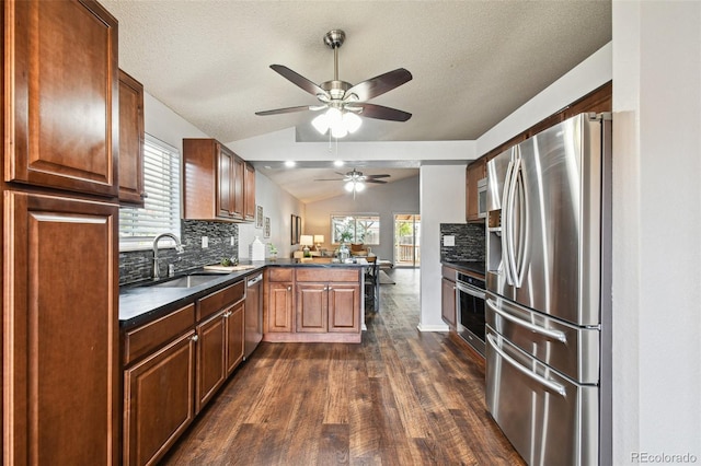 kitchen with vaulted ceiling, sink, backsplash, kitchen peninsula, and stainless steel appliances